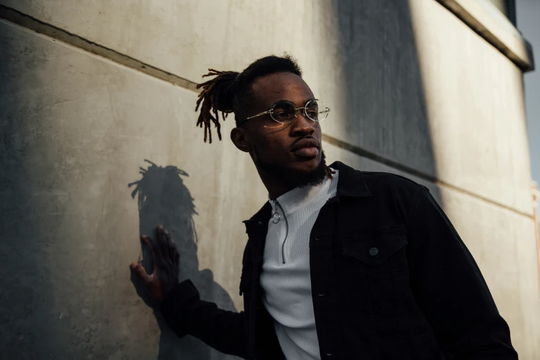 a man with dreadlocks standing against a building