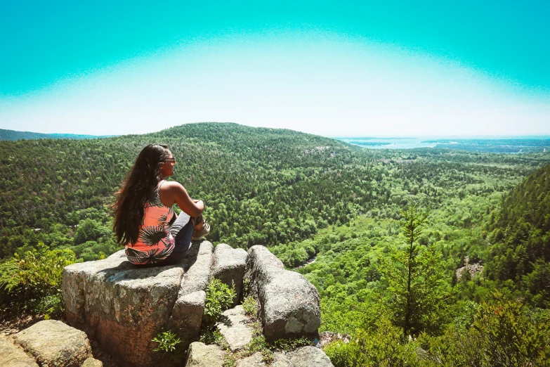 a woman sitting on top of a large boulder