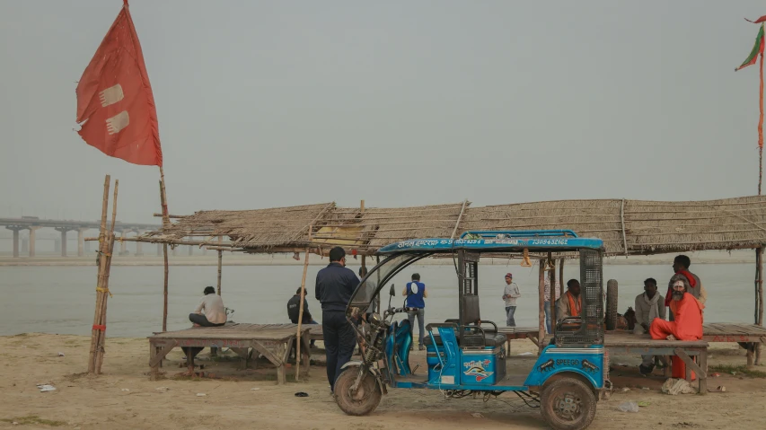 some people standing around a blue rickshaw