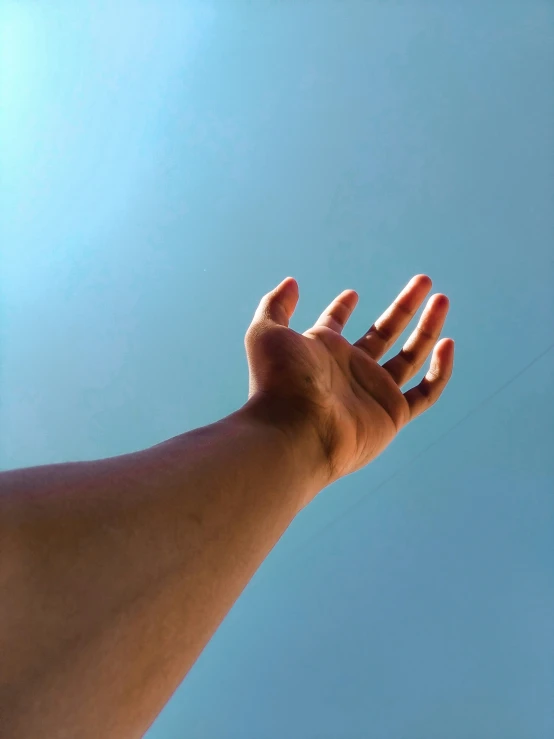 a hand is reaching up into the sky to hold a kite