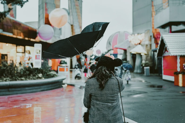 a woman is holding an umbrella while standing on a sidewalk