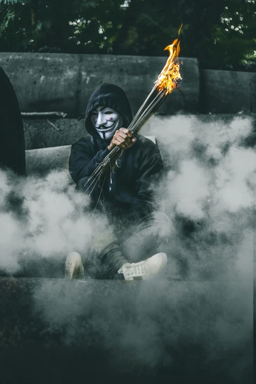 a person in costume and makeup with fire spear in a pile of smoke