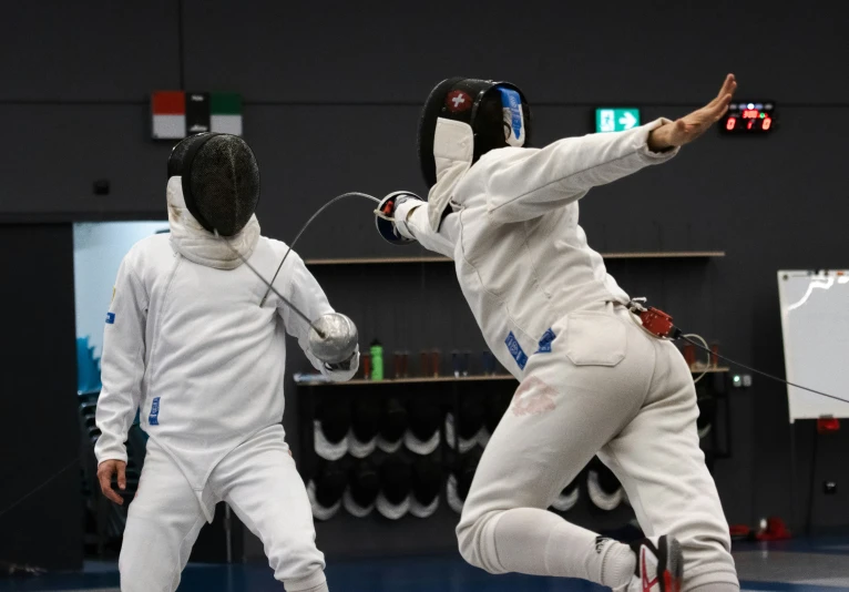 two men on fencing suits jumping for the ball