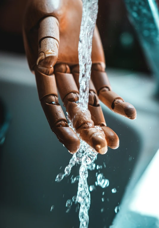 someone with their hand out and water spilling from the faucet