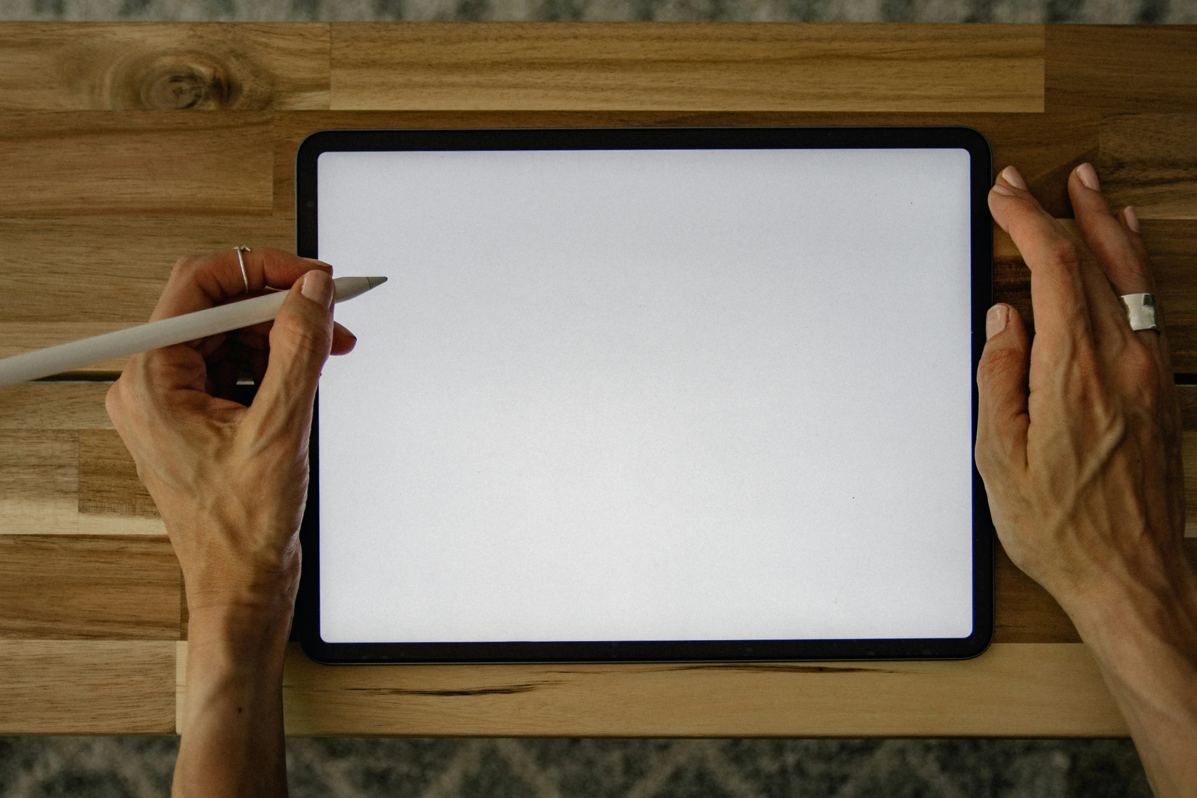 a person writing on a tablet and holding a pen