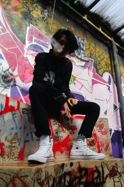 a person sitting on the side of a wall covered in graffiti