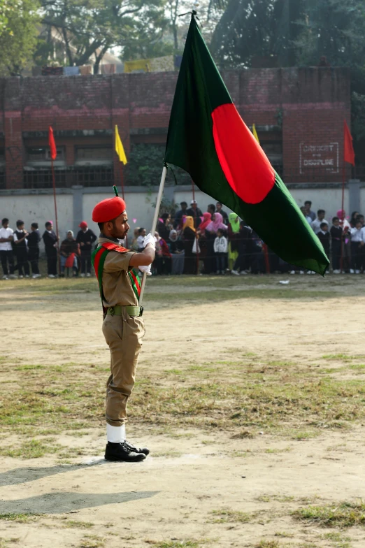 a boy holding the bangladesh flag, while a small group of people watch from the field
