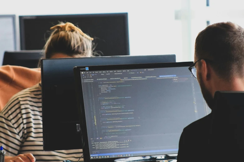 a man and woman are working on their computers