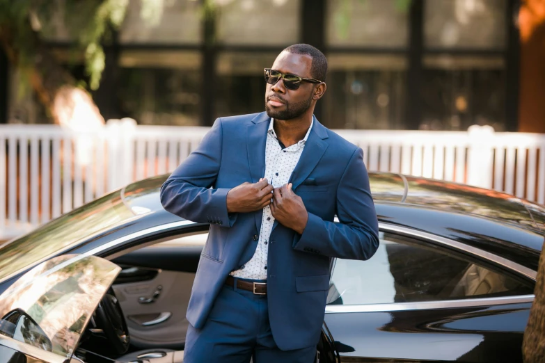 a black man standing next to a car