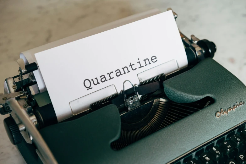 an old typewriter with a paper that reads quarantine