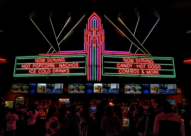 many people stand together in front of an illuminated sign