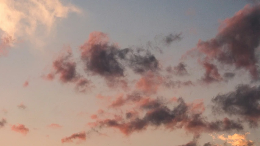 an airplane flying against a blue sky filled with clouds