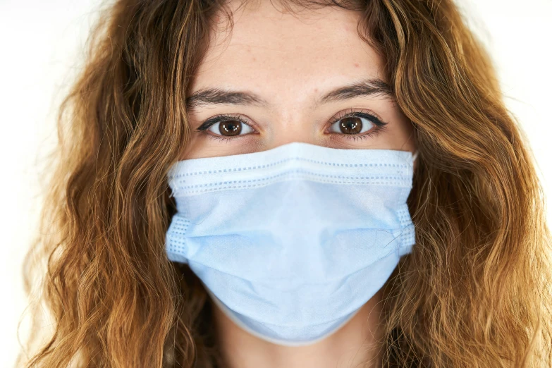 a woman wearing a blue face mask while looking at the camera