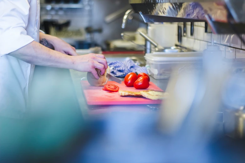 a chef chopping up tomatoes with a spoon in a kitchen