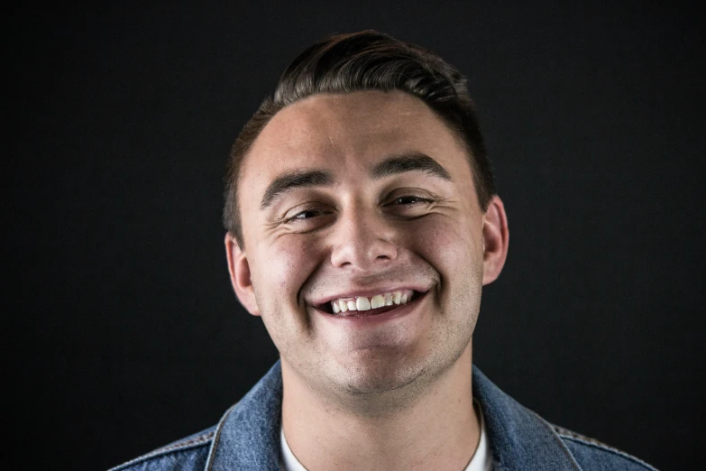 a young man smiles brightly at the camera