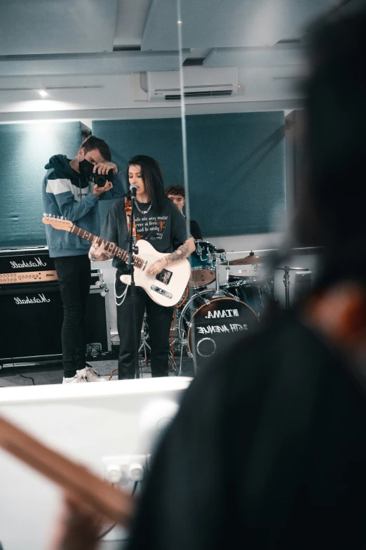 people playing guitar on a stage in front of a microphone