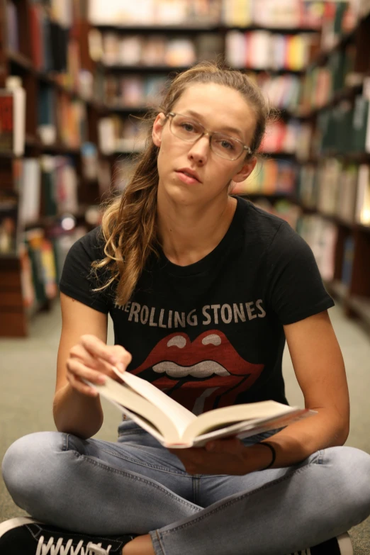a young woman sitting on the ground reading a book