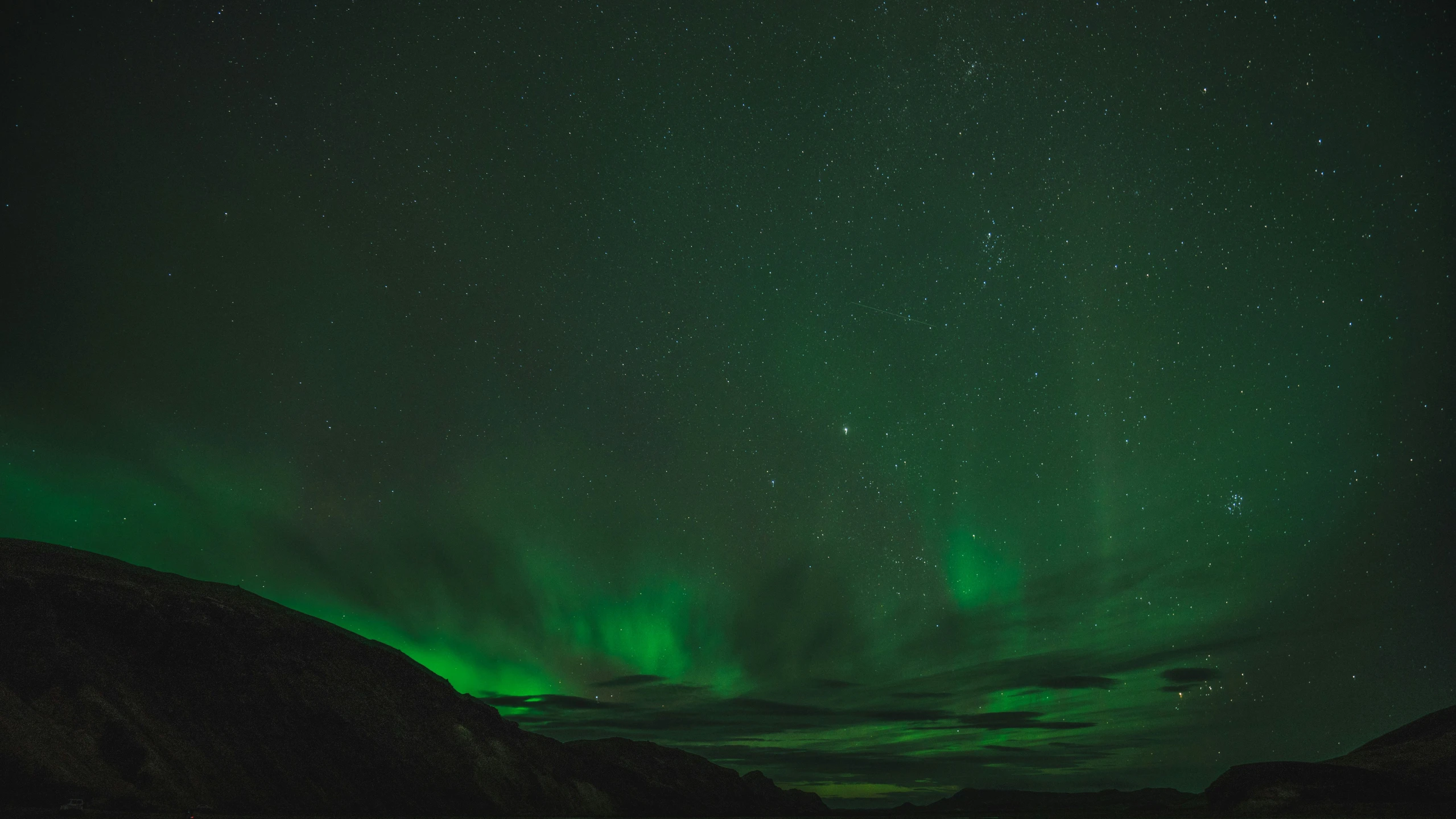 two lights glowing above green mountain under a starry sky