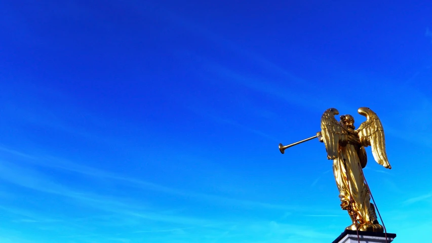 a tall golden statue in the middle of a blue sky