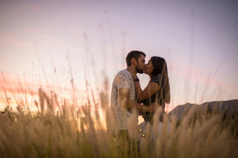 a woman kissing a man near the mouth in a field