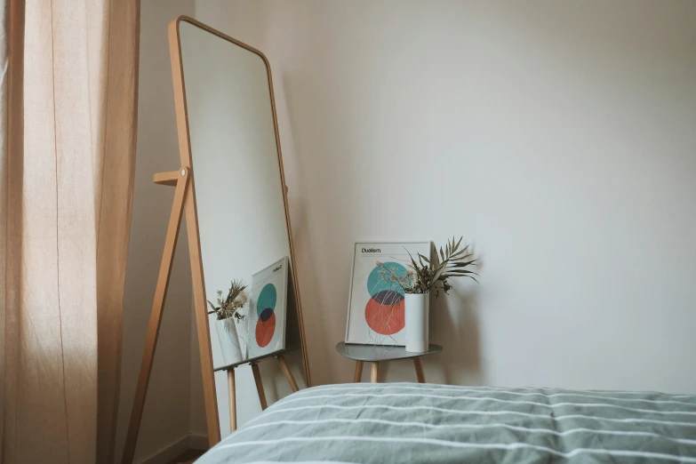 there is a mirror next to a plant on the nightstand