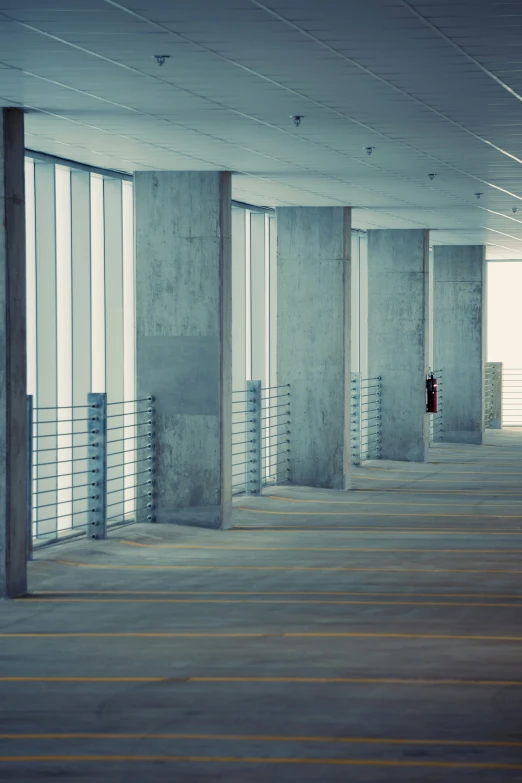 a lone person stands between two sets of windows in an empty building