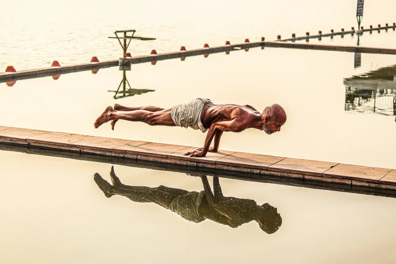 a man laying in the pool and bending over with his arms and legs