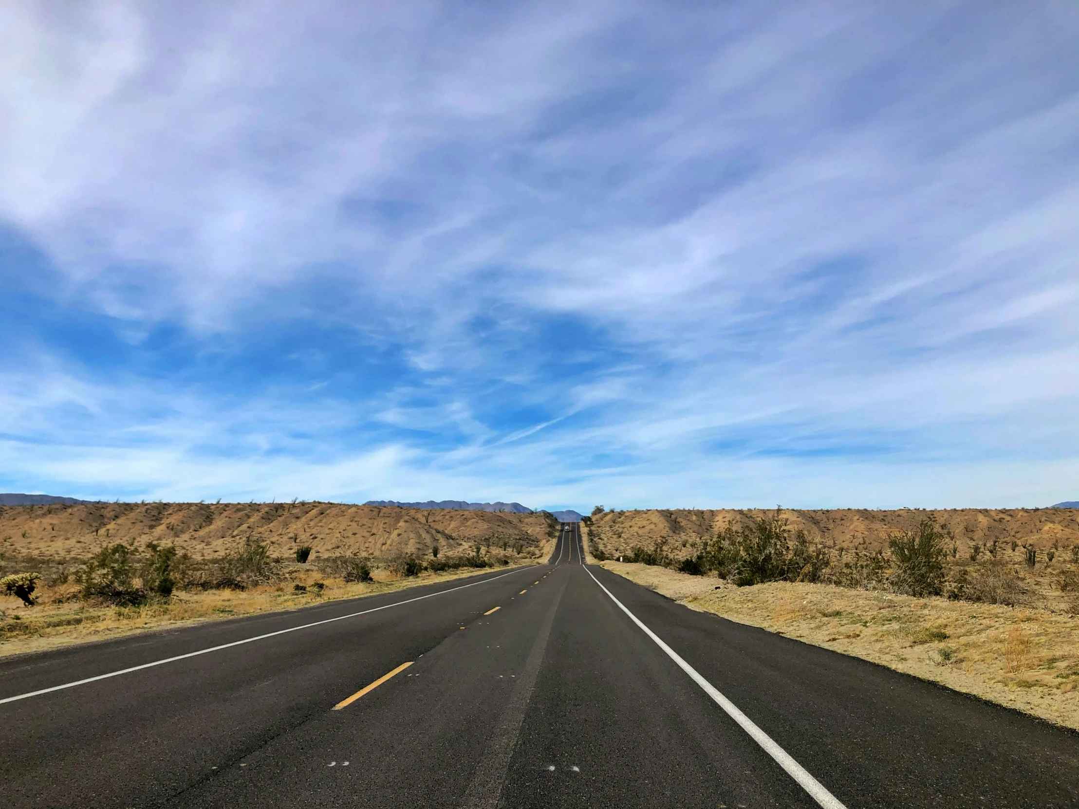 a highway with a sky filled with white clouds