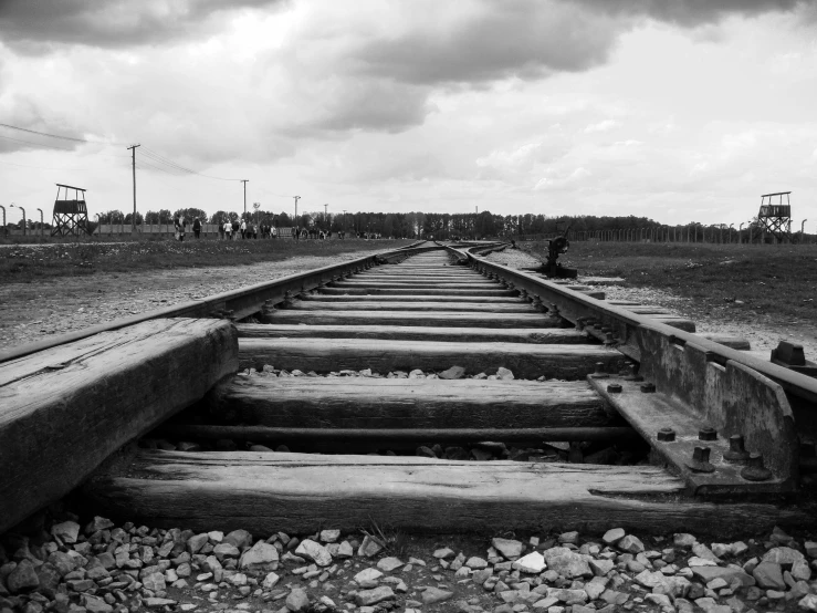 a person walking on a train track with a cloudy sky in the background