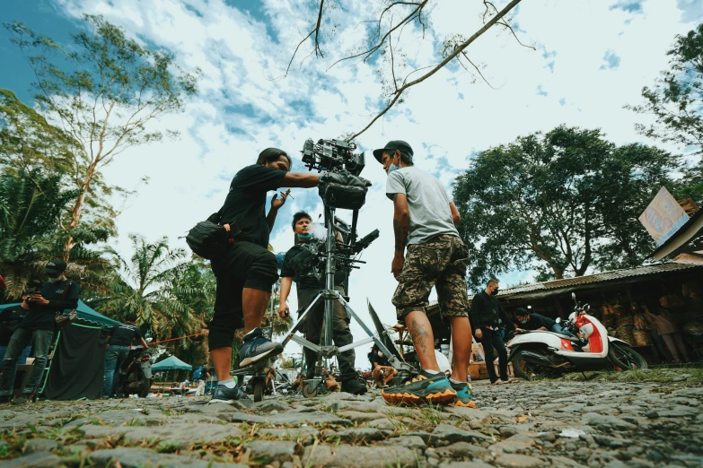 two men holding a video camera on top of a pile of rocks