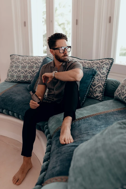 a man sitting on top of a blue couch wearing glasses