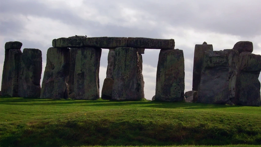 stonehenge, on the side of a hill under a cloudy sky
