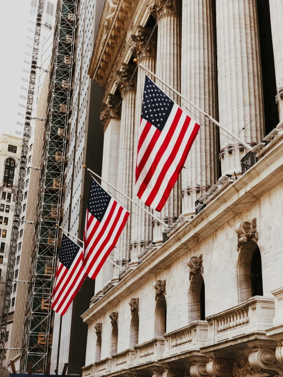 three american flags hang on a building in new york city