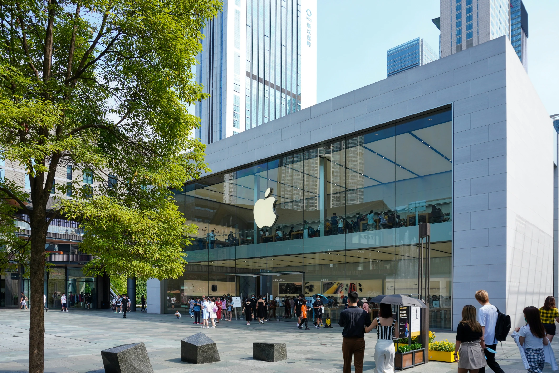 a group of people walking past an apple store