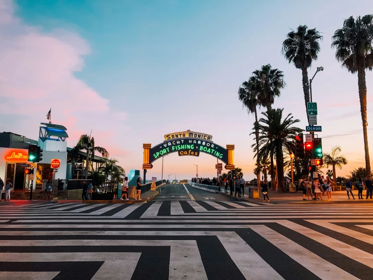 an intersection of people and street with the sun setting in the background