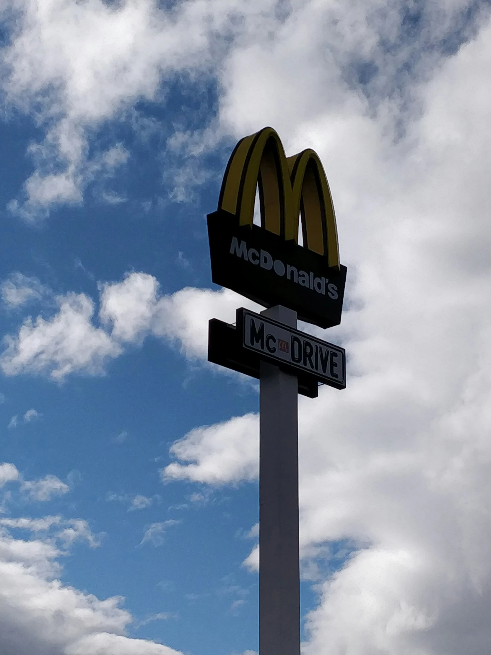 a mcdonalds sign in front of a cloudy blue sky