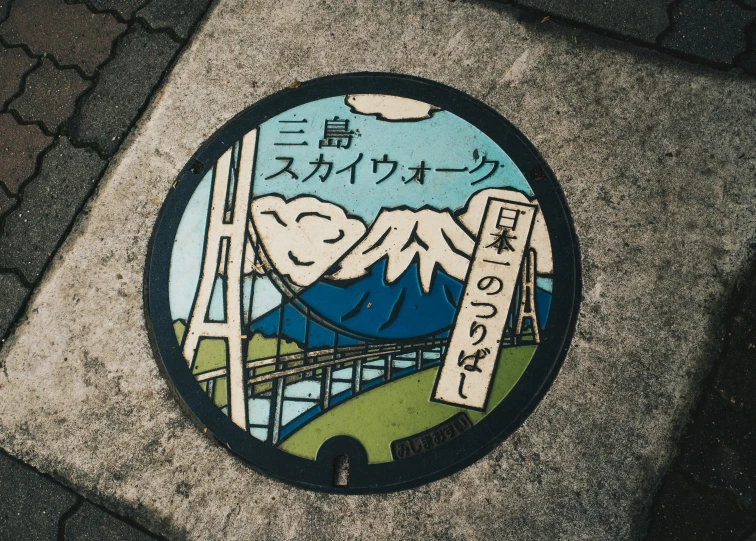 a circular picture on a sidewalk of a bridge and mountains