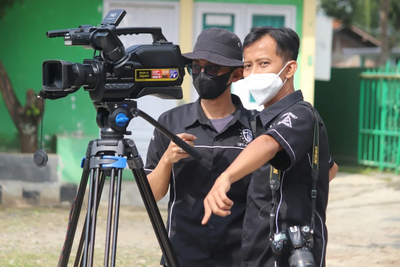 a cameraman wearing a protective mask talks with a man with a camera