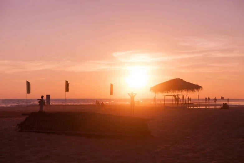 the sun setting on a beach next to a sandy shore