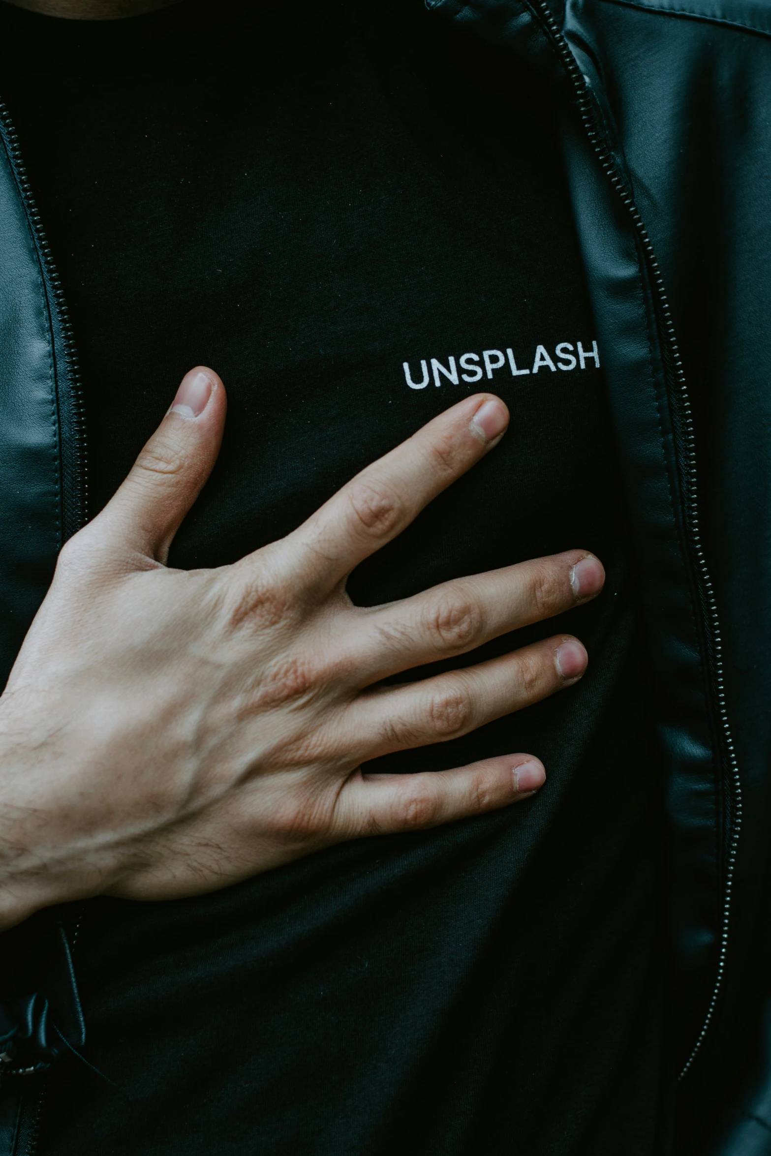 a man in black jacket with his hands on the chest