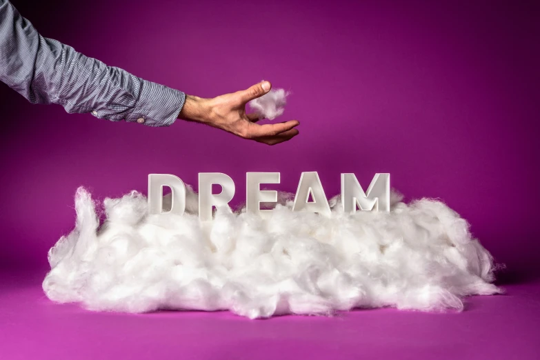 person touching fake clouds that spell out a dream