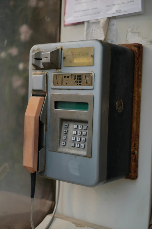 an old and dirty public phone with a wooden keypad attached