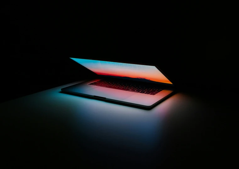 a black surface with a laptop glowing in the dark