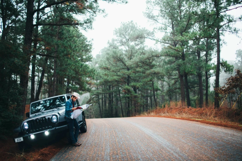 the girl is looking at a map while sitting in front of a jeep