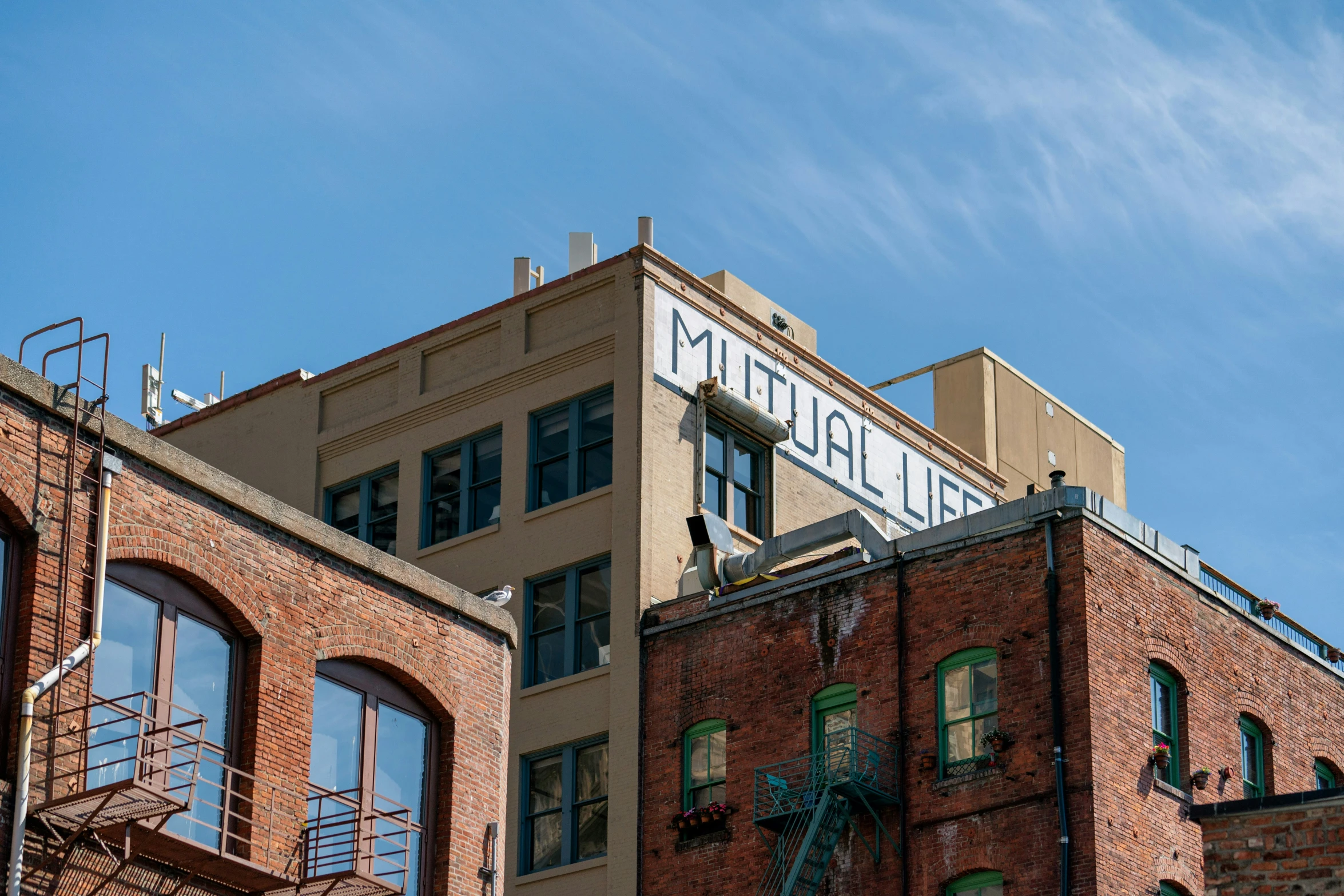 a brick building with a metal staircase is under a blue sky