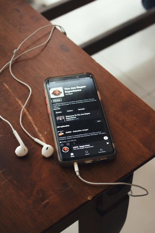 a cell phone and earphones on a wooden desk