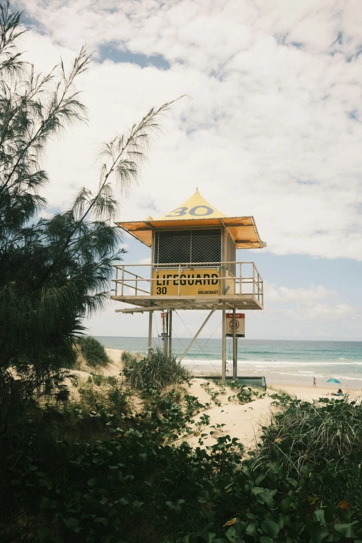 the life guard tower sits on a beach near a bush