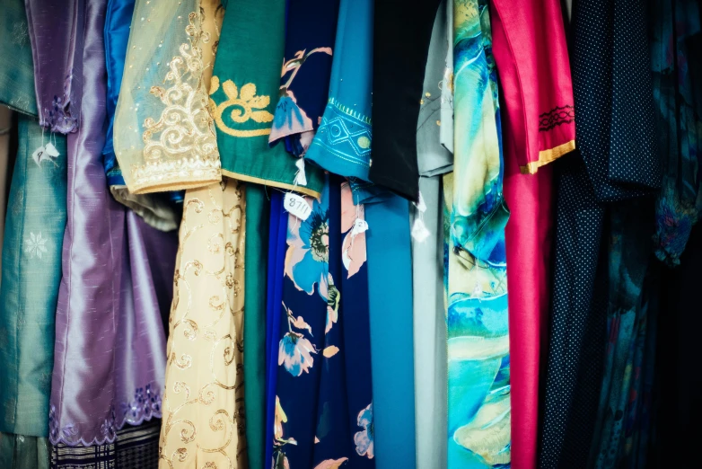 many different styles and colors of fabric hanging on rack