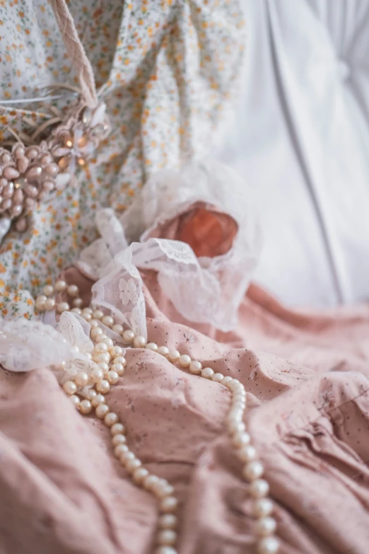 white pearls are strung around a pink fabric