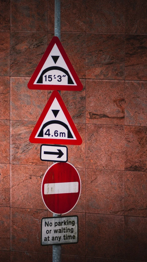 a variety of different street signs near a stone wall